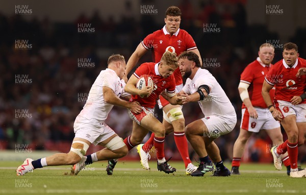 050823 - Wales v England - Vodafone Summer Series - Sam Costelow of Wales is tackled by Alex Dombrandt and Will Stuart of England 