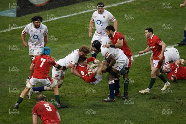 250223 - Wales v England - Guinness Six Nations - Josh Adams of Wales is tackled by Ollie Chessum and Maro Itoje of England