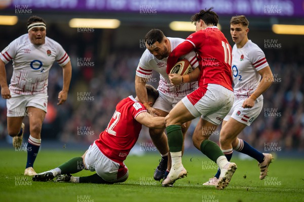 250223 - Wales v England - Guinness Six Nations - Ellis Genge of England is tackled by Joe Hawkins of Wales and Louise Rees-Zammit of Wales