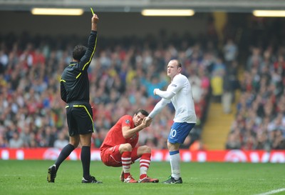 26.03.11 - Wales v England - Euro 2012 Qualifier - Wayne Rooney of England is shown a yellow card as he helps Joe Ledley of Wales to his feet. 