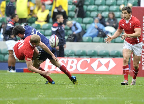 120513 - Wales v France - Bowl Final - HSBC Sevens World Series - Craoig Price of Wales, left, releases the ball to Alex Walker as he is tackled by Thibaut Zambelli of France 