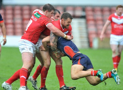 160612 - Wales v France  - Race Course Ground,  Wrexham - Jordan James of Wales, centre, lifts William Barthau of France off his feet