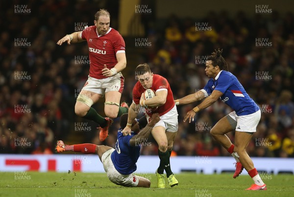 220220 - Wales v France - Guinness 6 Nations - Josh Adams of Wales is tackled by Virimi Vakatawa of France with Alun Wyn Jones jumping in the background