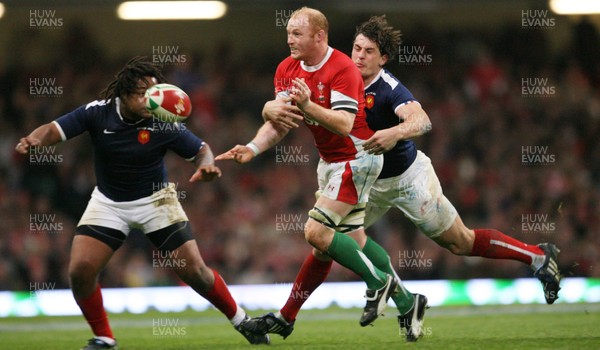 26.02.10 Wales v France... Wales' Martyn Williams passes under pressure from France's Mathieu Bastareaud and Julien Malzieu. 