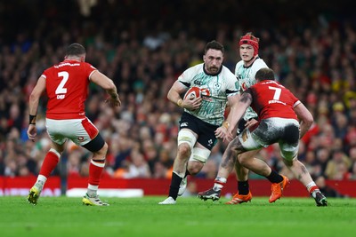 220225 - Wales v Ireland - Guinness Six Nations - Jack Conan  of Ireland runs with the ball whilst under pressure from Tommy Reffell and Elliot Dee of Wales