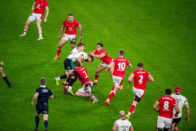 220225 - Wales v Ireland - Guinness Six Nations - Robbie Henshaw of Ireland is tackled by Tommy Reffell of Wales and Ben Thomas of Wales