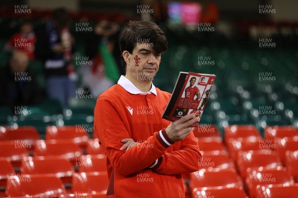 160324 - Wales v Italy - Guinness 6 Nations 2024 - Wales fan reads the programme 