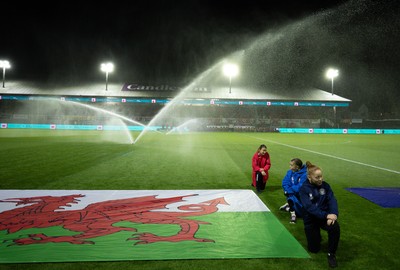 281025 - Wales v Poland, Women’s International Challenge Match - Members of the flag team at a soaking at the start of the match as the pitch sprinklers turn in their direction