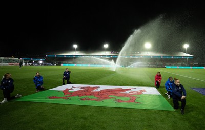 281025 - Wales v Poland, Women’s International Challenge Match - Members of the flag team at a soaking at the start of the match as the pitch sprinklers turn in their direction