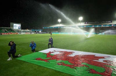 281025 - Wales v Poland, Women’s International Challenge Match - Members of the flag team at a soaking at the start of the match as the pitch sprinklers turn in their direction