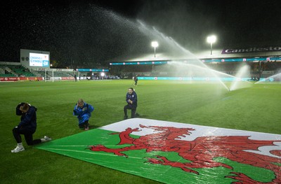 281025 - Wales v Poland, Women’s International Challenge Match - Members of the flag team at a soaking at the start of the match as the pitch sprinklers turn in their direction