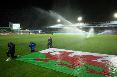 281025 - Wales v Poland, Women’s International Challenge Match - Members of the flag team at a soaking at the start of the match as the pitch sprinklers turn in their direction