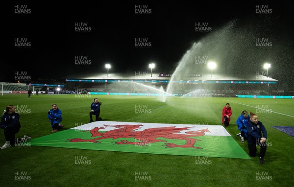 281025 - Wales v Poland, Women’s International Challenge Match - Members of the flag team at a soaking at the start of the match as the pitch sprinklers turn in their direction