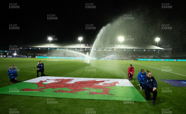 281025 - Wales v Poland, Women’s International Challenge Match - Members of the flag team at a soaking at the start of the match as the pitch sprinklers turn in their direction