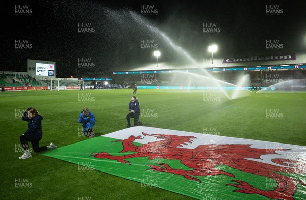 281025 - Wales v Poland, Women’s International Challenge Match - Members of the flag team at a soaking at the start of the match as the pitch sprinklers turn in their direction