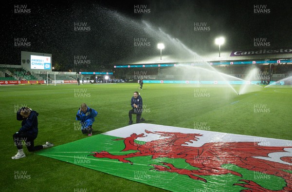281025 - Wales v Poland, Women’s International Challenge Match - Members of the flag team at a soaking at the start of the match as the pitch sprinklers turn in their direction