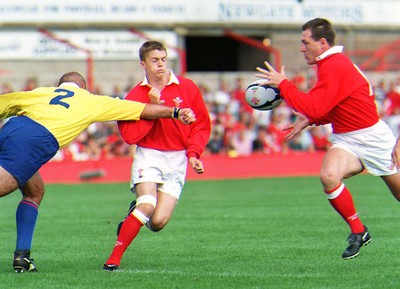 300897 - Wales v Romania - Arwel Thomas of Wales gets the ball away to Allan Bateman