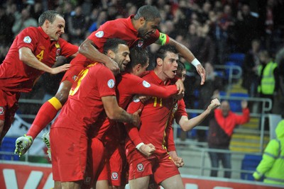 121012 - Wales v Scotland - FIFA 2014 World Cup Qualifying Campaign - Gareth Bale of Wales celebrates scoring the winner as he is mobbed by team mates 