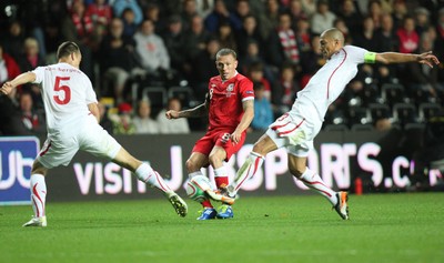 07.10.11 -  Wales v Switzerland, Euro 2012 Qualifying Match -  Wales' Craig Bellamy fires the ball between Switzerland's Steve Von Bergen and Switzerland's Gokhan Inler  