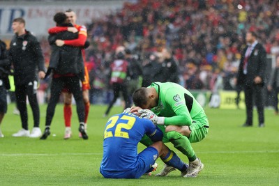 050622 -  Wales v Ukraine, World Cup Qualifying Play Off Final - Mykola Matviyenko of Ukraine in consoled by goalkeeper Georgiy Bushchan of Ukraine as Gareth Bale of Wales celebrates with Wales team mates