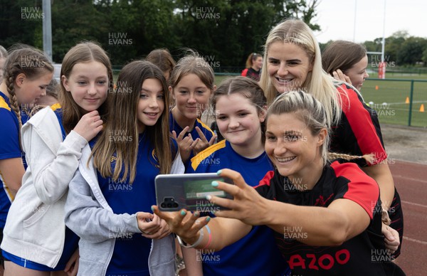130922 - Wales Women Captains Run - Lowri Norkett of Wales and Carys Williams-Morris of Wales pose with schoolchildren after they watched the Wales Women’s Captains Run ahead of the Women’s World Cup warm up match against England