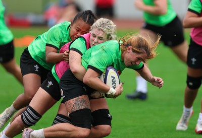 140926 Wales Women Rugby Training Session - Georgia Evans is tackled by Alex Callender and Jenna De Vera during a rugby training session ahead of the WXV matches against South Africa and USA