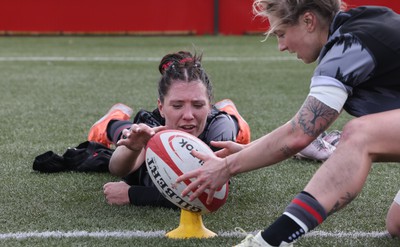 210323 - Wales Women Rugby Training Session - Georgia Evans helps Keira Bevan by steadying the ball during a training session ahead of Wales’ opening Women’s 6 Nations match against Ireland