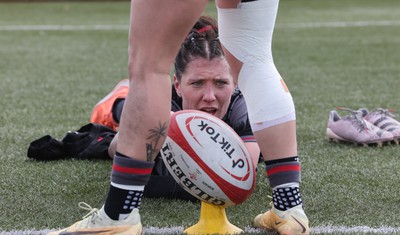 210323 - Wales Women Rugby Training Session - Georgia Evans helps Keira Bevan by steadying the ball during a training session ahead of Wales’ opening Women’s 6 Nations match against Ireland