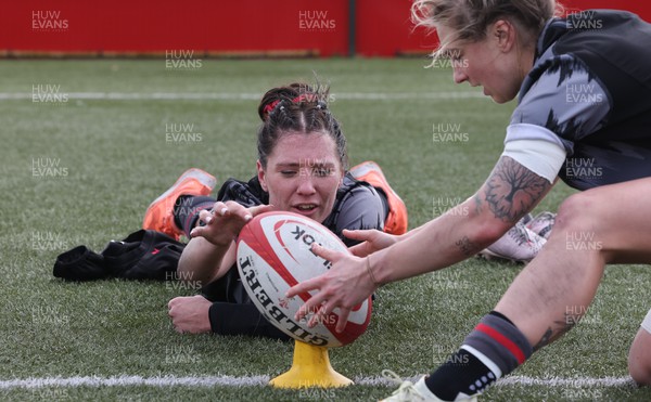 210323 - Wales Women Rugby Training Session - Georgia Evans helps Keira Bevan by steadying the ball during a training session ahead of Wales’ opening Women’s 6 Nations match against Ireland