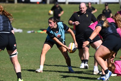 240725 - Wales Women Rugby Training at The Southport School, Southport - Nel Metcalfe is watched by Sean Lynn, Wales Women head coach during a Wales Womens Rugby training session ahead of their first tour match against Australia