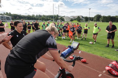 240823 - Wales Women Training session - Team mates look on as Carys Williams-Morris finishes a set on the bike during training session