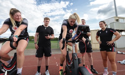 240823 - Wales Women Training session - Team mates look on as Carys Williams-Morris finishes a set on the bike during training session