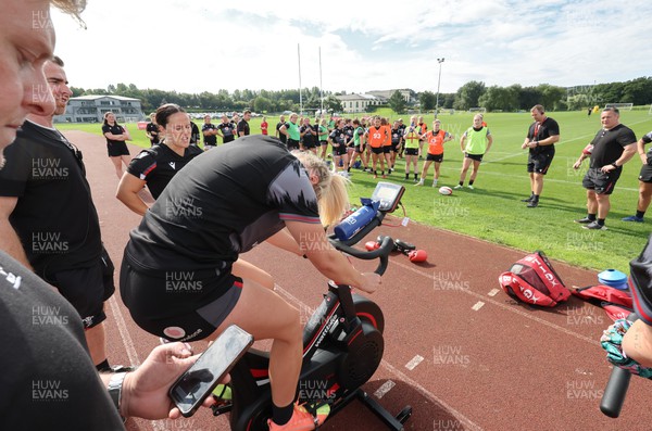 240823 - Wales Women Training session - Team mates look on as Carys Williams-Morris finishes a set on the bike during training session