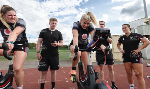 240823 - Wales Women Training session - Team mates look on as Carys Williams-Morris finishes a set on the bike during training session