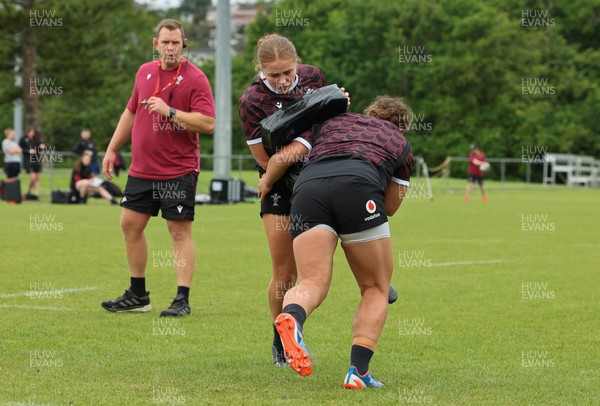 301023 - Wales Women Rugby Training Session - Niamh Terry and Lleucu George work as head coach Ioan Cunningham looks on during a training session at Pakuranga United RFC ahead of their WXV1 match against Australia