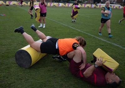 260825 - Wales Women Rugby World Cup Training Session - Shaun Connor, Wales Women attack coach takes a hit from Gwenllian Pyrs during a Wales training session ahead of their Women’s Rugby World Cup match against Canada