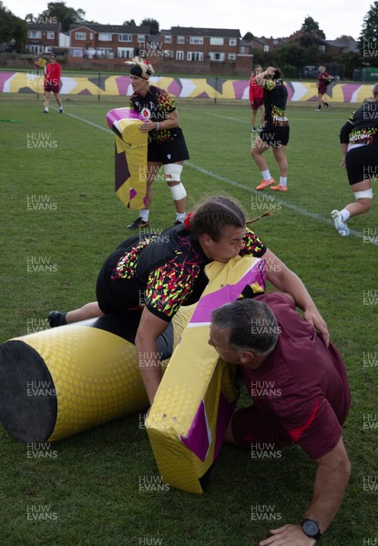 260825 - Wales Women Rugby World Cup Training Session - Shaun Connor, Wales Women attack coach takes a hit from Carys Phillips during a Wales training session ahead of their Women’s Rugby World Cup match against Canada