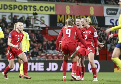 250225 - Wales v Sweden - UEFA Women's Nations League - Kayleigh Barton of Wales (9) celebrates scoring the equalising penalty with teammates