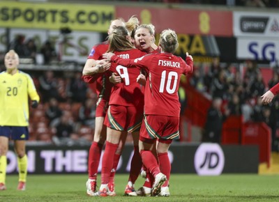 250225 - Wales v Sweden - UEFA Women's Nations League - Kayleigh Barton of Wales (9) celebrates scoring the equalising penalty with teammates