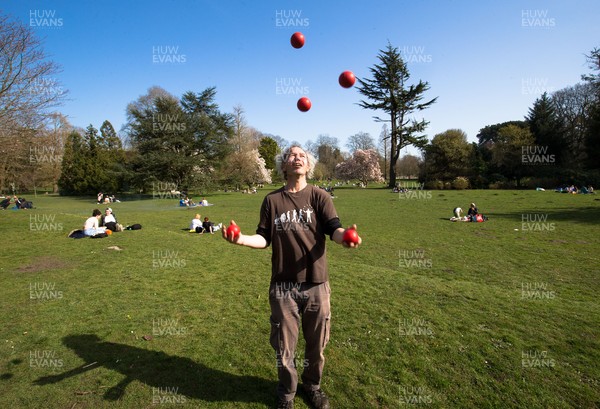300321 Warm weather, Cardiff - Juggler Tom Kellett practises his skills as people enjoy the warm weather and the fact that lockdown regulations have been eased in Wales as they gather with family and friends in Bute Park, Cardiff