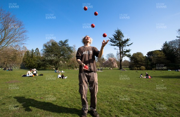 300321 Warm weather, Cardiff - Juggler Tom Kellett practises his skills as people enjoy the warm weather and the fact that lockdown regulations have been eased in Wales as they gather with family and friends in Bute Park, Cardiff